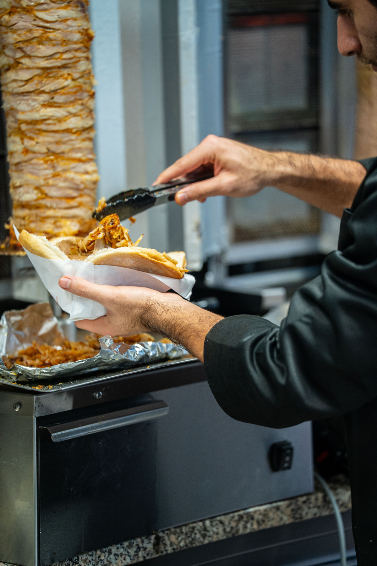 Frisches Dönerfleisch wird auf den Döner gelegt